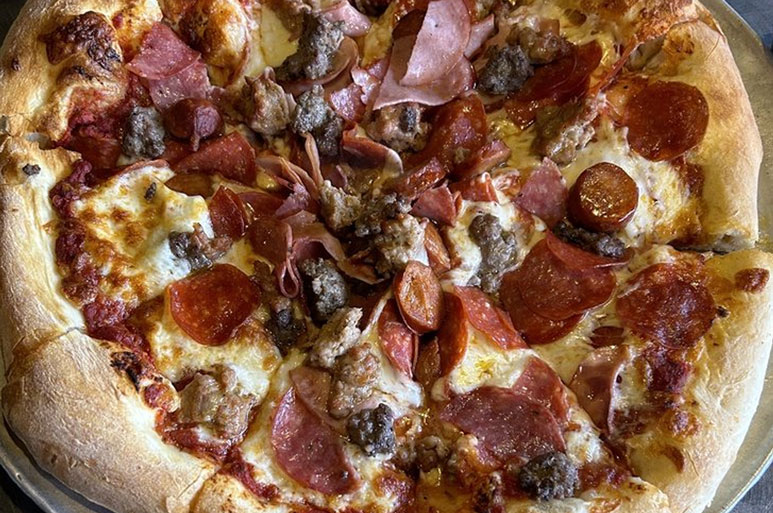 A pizza topped with a bunch of meat